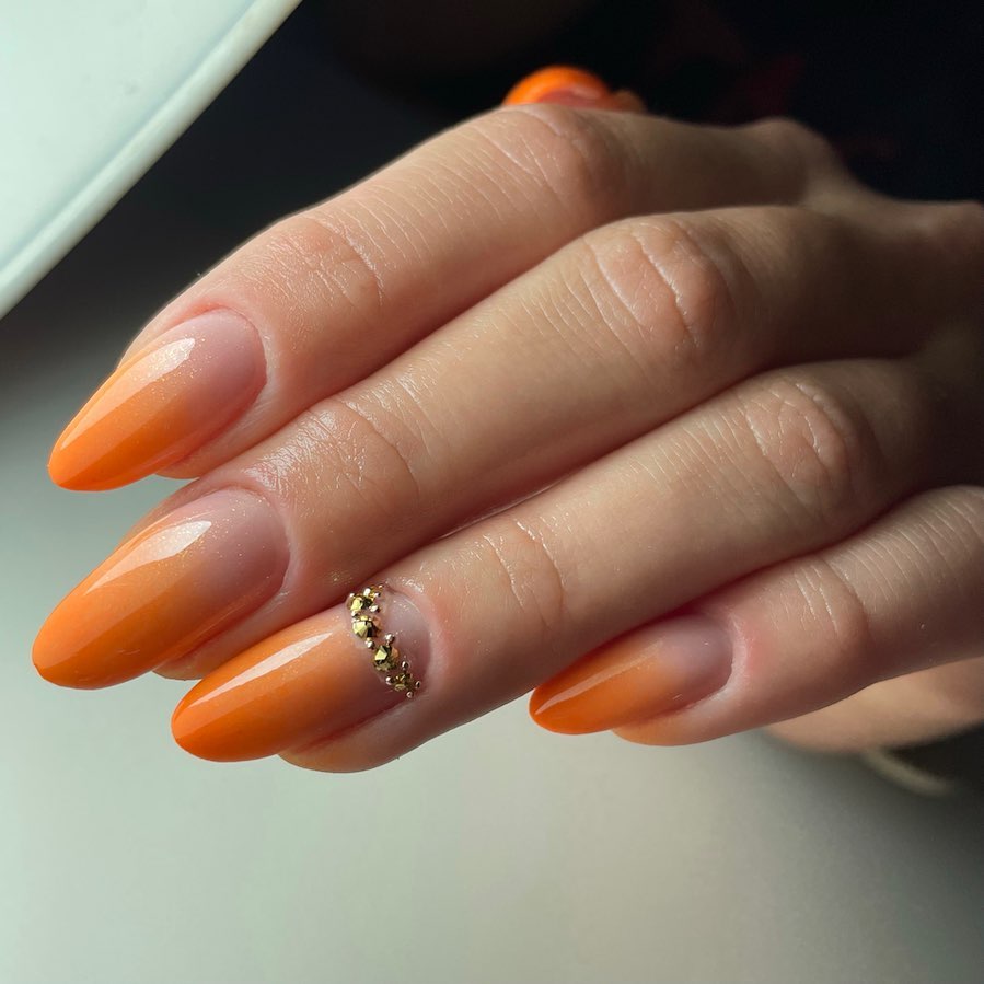 Glossy Orange Ombre Almond Nails with Gold Rhinestone Charm