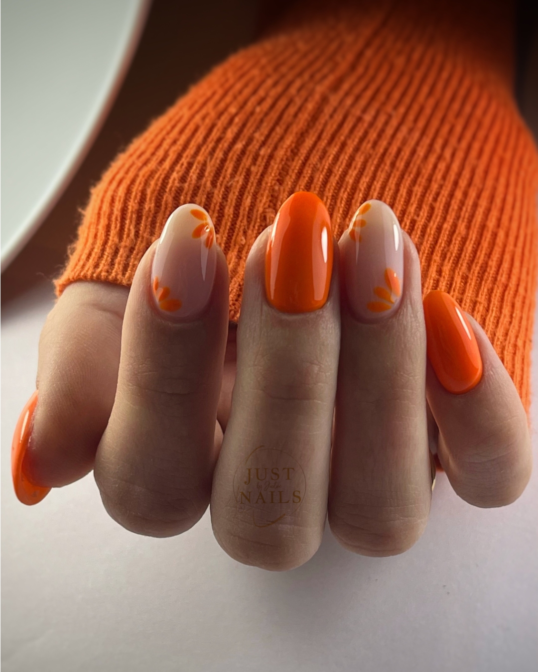 Vibrant Orange Glossy Almond Nails with Daisy Accents